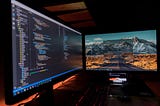 A picture of two monitors one is showing code and the other is showing a user interface