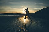 Someone leaping towards water on a beach