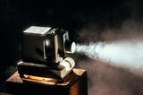 A film projector turned on, with the light visibly cutting through fog