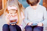 Twee kinderen die op hun smartphone spelen.
