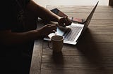 person doing content writing on laptop, coffee mug on the table