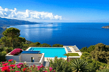 A stunning villa in Mallorca with panoramic sea views, surrounded by lush greenery and vibrant flowers, embodying the essence of paradise living.