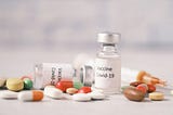 Two vials of COVID-19 vaccination material is among several pills and tablets.