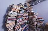 Leaning towers of books held together by rubber bands