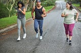 Three runners jogging down the road in conversation
