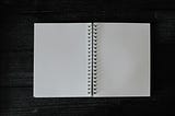 Open spread of blank pages in a spiral-bound notebook.