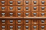 an ancient file cabinet with many labeled drawers.