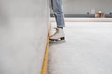 A skater stands next to the wall.