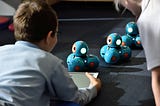 A kid controlling robots with a tablet of some sort.