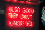 A red neon sign that says “Be so good they can’t ignore you”