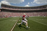 A fotball receiver tries to outrace opponent down the sidelines during a football game.