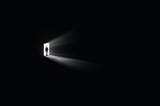 a man entering the dark room and shedding the light from the other room