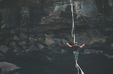 Climber on a rope balancing as he walks over a river