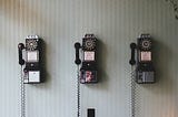 This is a photo of 3 old fashioned coin telephones
