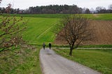 2 people walking down a lonely road path