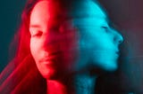 Two blurred images of the same face turning, in red and blue