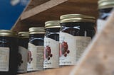 Wooden shelf with row of jam jars.