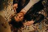 Man in Black Leather Jacket Lying On Floor Covered in Confetti