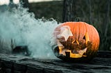 Pumpkin burning from the inside and a haunted house in the background