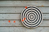 A game of darts: Red feathered darts on a circular board with numbered spaces