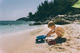 Kid playing with a truck in the sand.