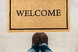 A welcome mat with two feet planted in front.