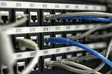 The back of a large, multi-tiered switch with ethernet cords.