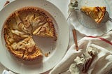 A picture of an apple pie on a plate with a slice cut out