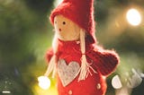 A toy elf hanging on a Christmas tree.