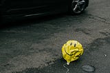 smiley face deflated balloon on the side of a road