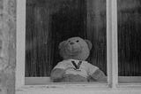 Sad teddy bear sitting in window