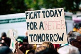 A climate protestor with a sign that reads Fight Today For a Better Tomorrow