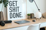 A work desk with a frame that says ‘Get Shit Done’