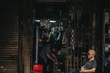 A shop keeper sits outside his ramshackle store in SouthEast Asia