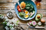 A healthy meal featuring fruits and veggies on a blue plate, situated on a wooden surface.