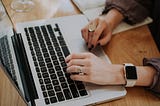 woman’s hands typing on a laptop keyboard