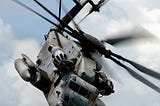 grey helicopter in cloudy sky with helicopter blades in motion; posted on 2024 mickey markoff article on aviation history month