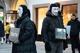 people with vendetta masks holding truth signs.