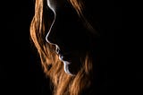 Foto da autoria de Christian Holzinger encontrada no Unsplash. Essa foto foi escolhida para simbolizar a iluminação com luz de fundo, que, nessa fotografia ilumina uma mulher branca com cabelos alaranjados.