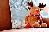 A stuffed Christmas reindeer sitting on a chair.