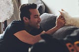 A man petting a cat on a couch