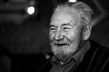 an old man smiling in a black and white picture