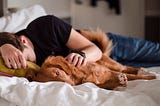 Man asleep with his dog lying next to him.