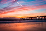 A view of Hermosa Beach during a sunset with a bridge blocking the view.