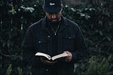 Man in cap and jacket reading Bible