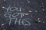 Asphalt with dry leaves and chalk writing. “YOU GOT THIS”