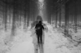 A blurry black and white image of a person in the woods.