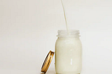 Milk with a straw in a glassware with its cap on the left side inclined to it.