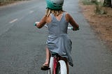 Young girl riding a bike down the road photo taken from the back