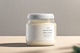 A jar of white cream sits on a clean, minimalist table, with soft natural light illuminating the label